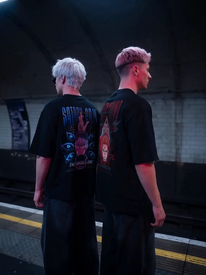 Two models in the Gojo and Sukuna Prime II oversized tees on a subway platform